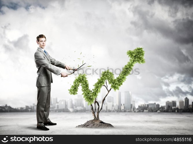 Growth concept. Young businessman cutting bush in shape of graph