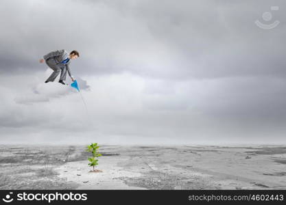 Growth concept. Young businessman standing on cloud and watering sprout