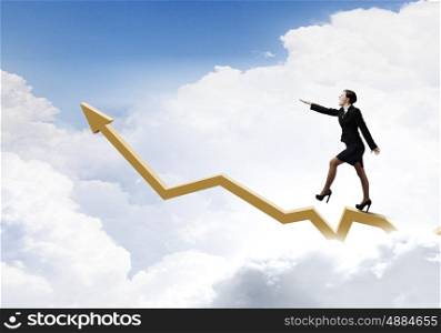 Growth concept. Young cheerful businesswoman walking on increasing graph