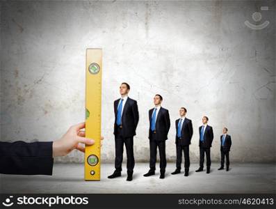 Growth in business. Close up male hand measuring miniatures of businesspeople