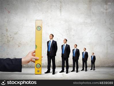 Growth in business. Close up male hand measuring miniatures of businesspeople