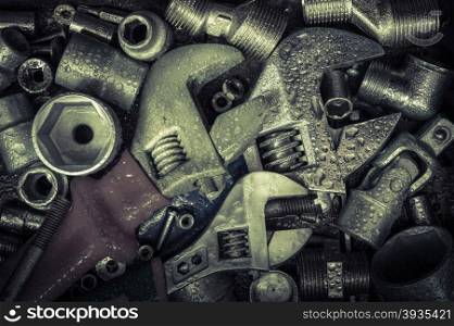 Grunge background with wet tools and bolts. Adjustable wrench, screws, nuts. Toned.
