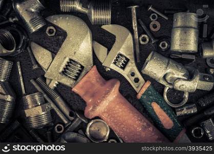 Grunge background with wet tools and bolts. Adjustable wrench, screws, nuts. Toned.