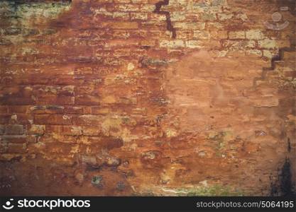 Grunge brick wall with peeling orange paint on an old house
