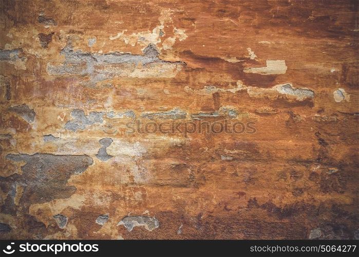 Grunge old wall with orange paint peeling off the weathered brick wall