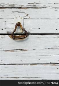 Grunge picture of an old rusty doorknocker on a wooden door, background with copy space.