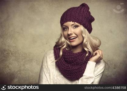 grunge portrait of young and sexy blond girl wearing purple scarf and hat in winter dress over white