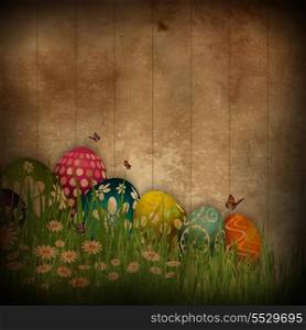 Grunge style design of Easter eggs in grass against a wooden background