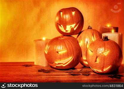 Grunge style photo of a carved pumpkins with scary faces and glowing candles on the table, festive party decoration for Halloween holiday