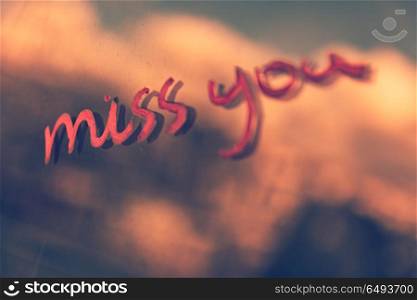 "Grunge style photo of a handwritten phrase "miss you", conceptual image of a happy love and nostalgia. Miss you"