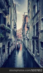 Grunge style photo of an old narrow Venetian street, beautiful aged buildings over water canal, romantic destination, Venice, Italy