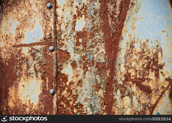 Grunge texture: old rusty metal surface covered with blue paint flaking and cracking texture, with seam and rivets