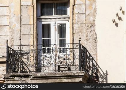 Grunge weathered old crumbling balcony with wooden door of neglected townhouse