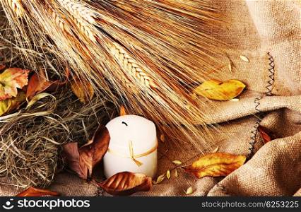 Grunge wheat background with autumn leaves &amp; candle