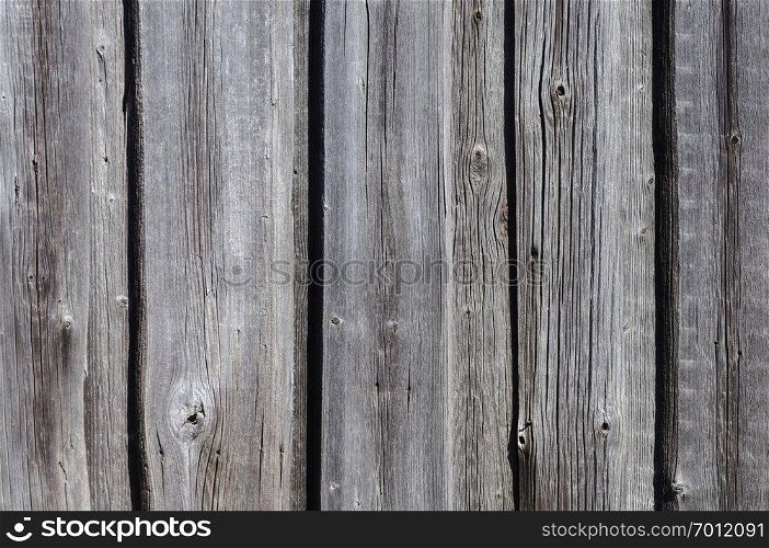 Grunge wooden background. Fragment of an old gray wooden fence.