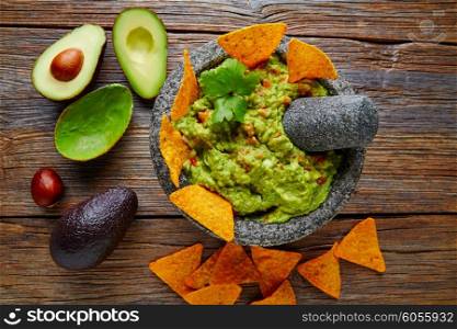 Guacamole with nachos avocado in Mexican molcajete in aged wood table