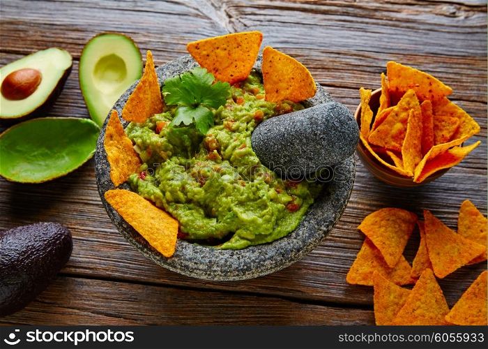 Guacamole with nachos avocado in Mexican molcajete in aged wood table
