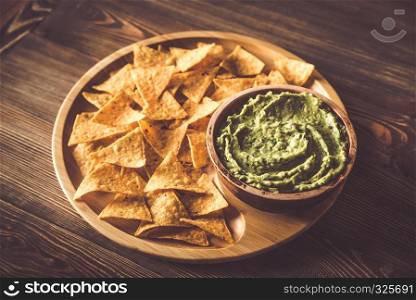 Guacamole with tortilla chips on the wooden tray