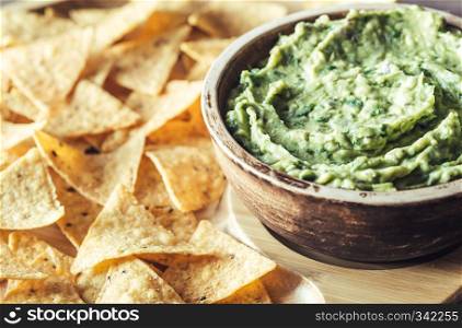 Guacamole with tortilla chips on the wooden tray