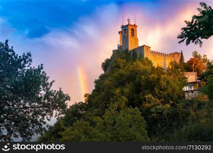 Guaita fortress or Prima Torre on the ridge of Mount Titano, in the city of San Marino of the Republic of San Marino at gorgeous sunset with rainbow. Guaita fortress in San Marino