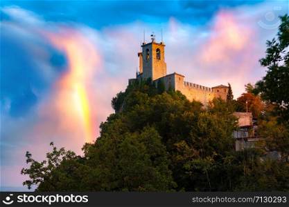 Guaita fortress or Prima Torre on the ridge of Mount Titano, in the city of San Marino of the Republic of San Marino at gorgeous sunset with rainbow. Guaita fortress in San Marino