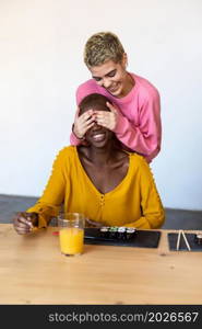 Guess who Beautiful woman covering eyes of her female friend and smiling. Guess who Beautiful young woman covering eyes of her female friend and smiling