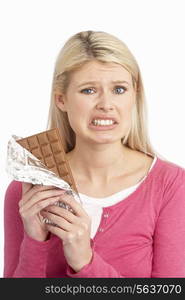 Guilty Looking Young Woman Eating Big Bar Of Chocolate In Studio