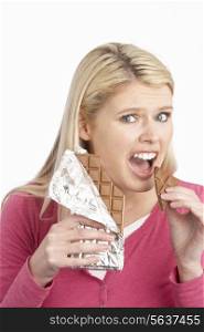 Guilty Looking Young Woman Eating Big Bar Of Chocolate In Studio