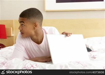 Guilty Teenage Boy Using Laptop In Bedroom