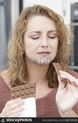 Guilty Woman On Diet Eating Chocolate Bar At Home