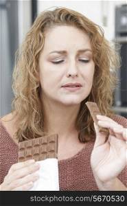 Guilty Woman On Diet Eating Chocolate Bar At Home