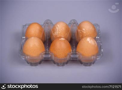 Guinea fowl eggs in plastic packaging on a gray background.