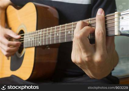 Guitar Player Hand or Musician Hand in F Major Chord on Acoustic Guitar String with soft natural light in side view