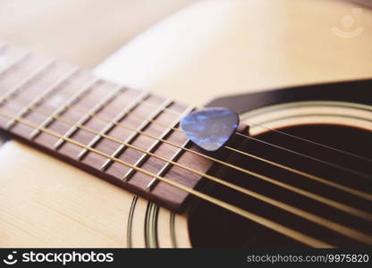 Guitar resting on old wooden background, Close up acoustic guitar and Guitar pick Home hobbies concept