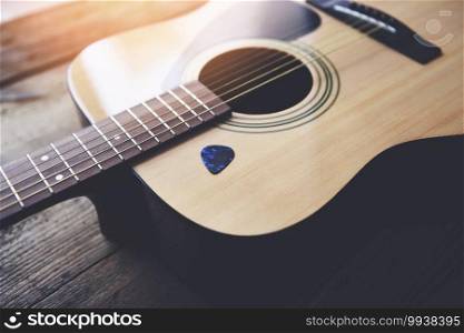 Guitar resting on old wooden background, Close up acoustic guitar and Guitar pick