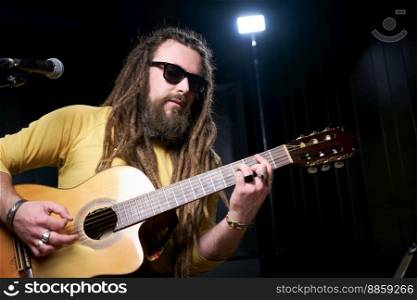 Guitarist man plays an acoustic guitar Close-up at studio.. Guitarist man plays an acoustic guitar Close-up at studio