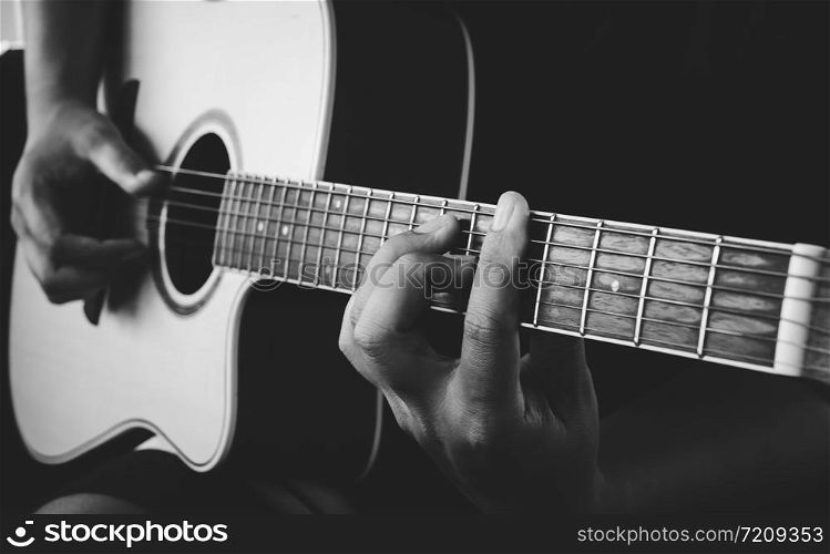 guitarist&rsquo;s hand on strings on dark background
