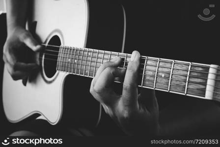 guitarist&rsquo;s hand on strings on dark background