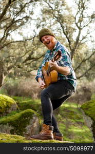 Guitarist with crazy face playing the guitar in the forest