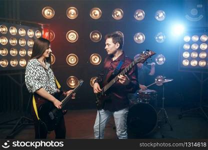 Guitarists plays on electric and bas guitar, stage with lights on background. Rock band. Guitarists plays on electric and bas guitar