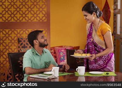 Gujrati woman serving dhokla to her husband during breakfast