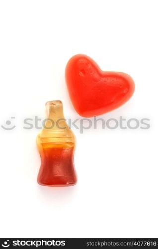 Gummy cola bottles and heart candy on white background