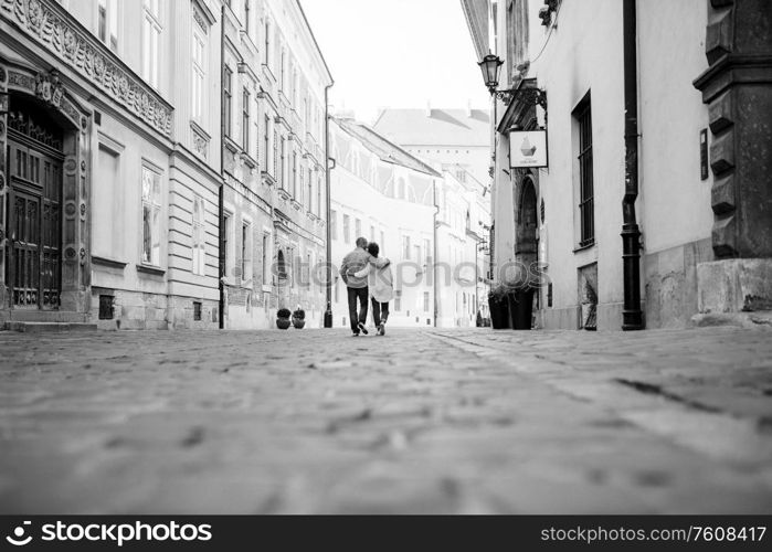 guy and a girl happily walk in the morning on the empty streets of old Europe