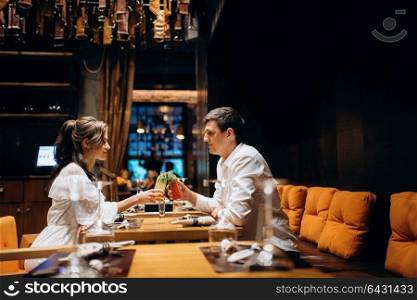 guy and a girl have lunch in a cafe and drink cocktails