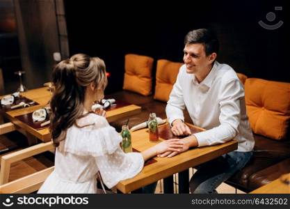 guy and a girl have lunch in a cafe and drink cocktails