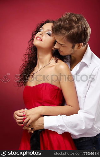 Guy embraces the girl behind on a red background