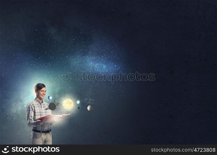 Guy exploring space. Young man with book and planets of space spinning around