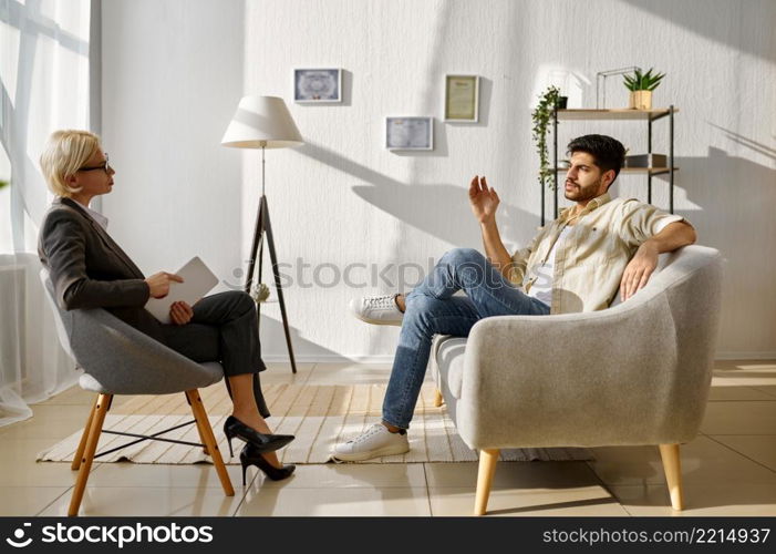 Guy gesturing hand explaining something talk to doctor psychologist. Therapist listening carefully. Emotional guy gesturing talking to doctor psychologist