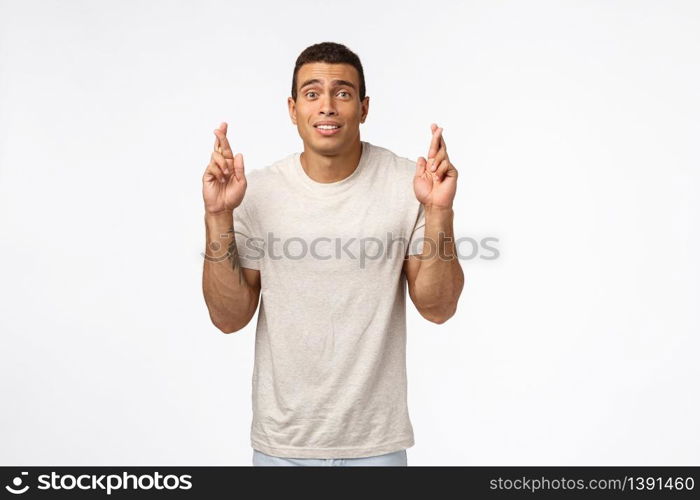 Guy hopes to get football sports scholarship in college. Strong handsome athletic man in t-shirt, cross fingers good luck and look worried awaiting important results, anticipate wish come true.. Guy hopes to get football sports scholarship in college. Strong handsome athletic man in t-shirt, cross fingers good luck and look worried awaiting important results, anticipate wish come true