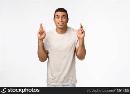 Guy hopes to get football sports scholarship in college. Strong handsome athletic man in t-shirt, cross fingers good luck and look worried awaiting important results, anticipate wish come true.. Guy hopes to get football sports scholarship in college. Strong handsome athletic man in t-shirt, cross fingers good luck and look worried awaiting important results, anticipate wish come true